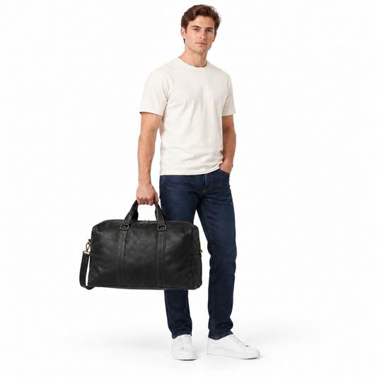 Casually dressed male model holding the black Gael leather duffle bag against a white background