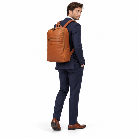 Male model in a navy suit wearing the brown Alex leather backpack against a white background